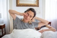 Woman in Gray Shirt stretching in Bed