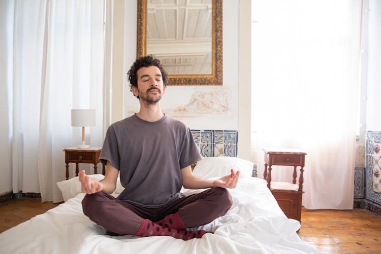 A Man Meditating On The Bed