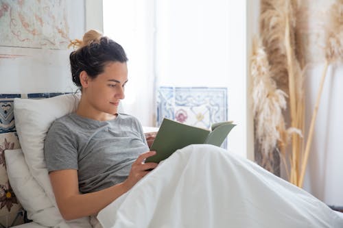 A Woman Reading a Book in the Bed 