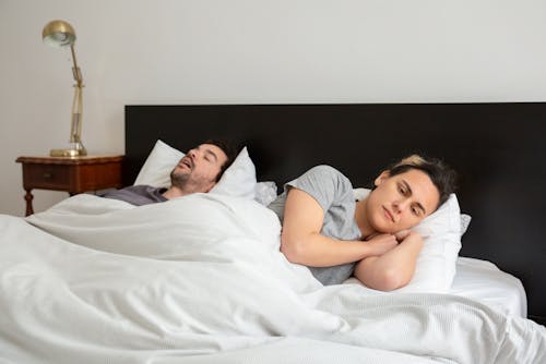 Free A Couple Lying Down in Bed Stock Photo