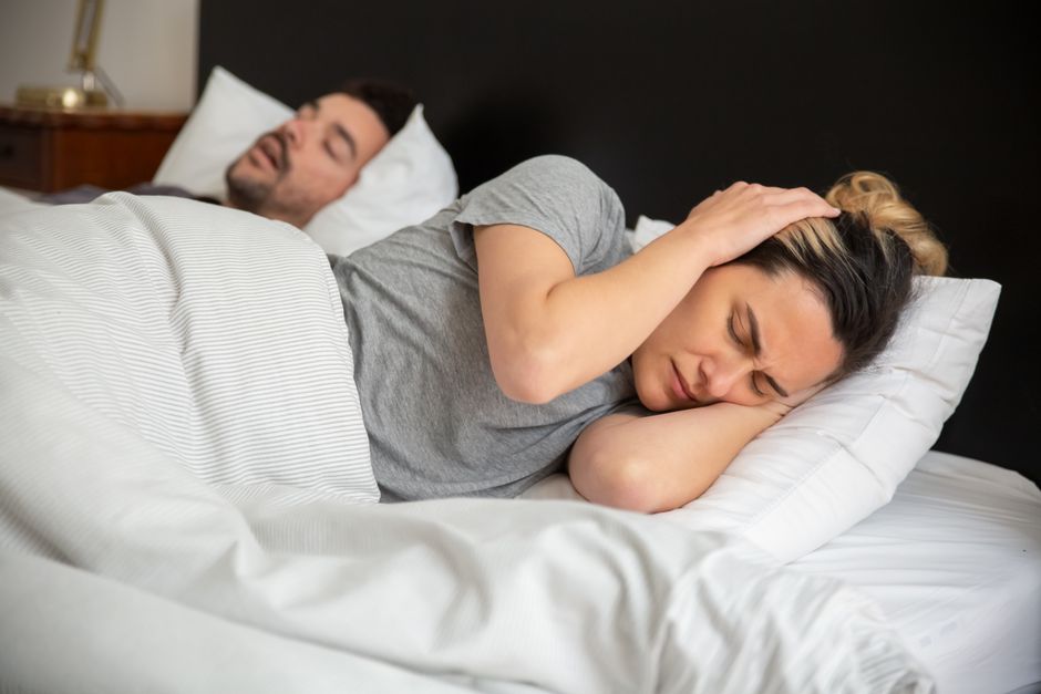 Urządzenie white noise na stoliku nocnym w sypialni z miękkimi tekstyliami