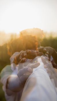 A creative double exposure photo capturing hands reaching out with blurred effects, outdoors at sunset.
