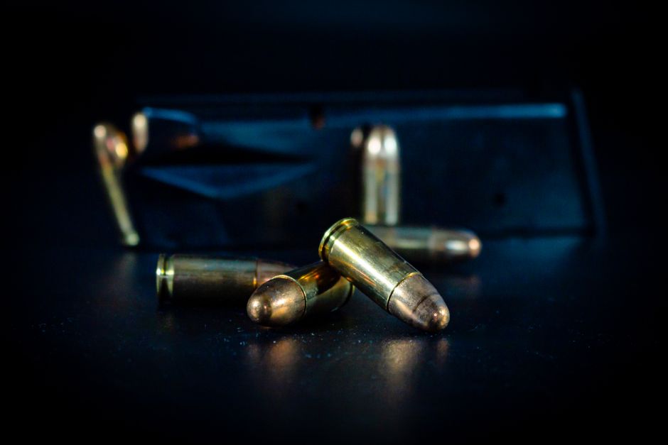 Fotomural Una foto macro de balas y un cargador de arma sobre una superficie oscura, resaltando la textura metálica.