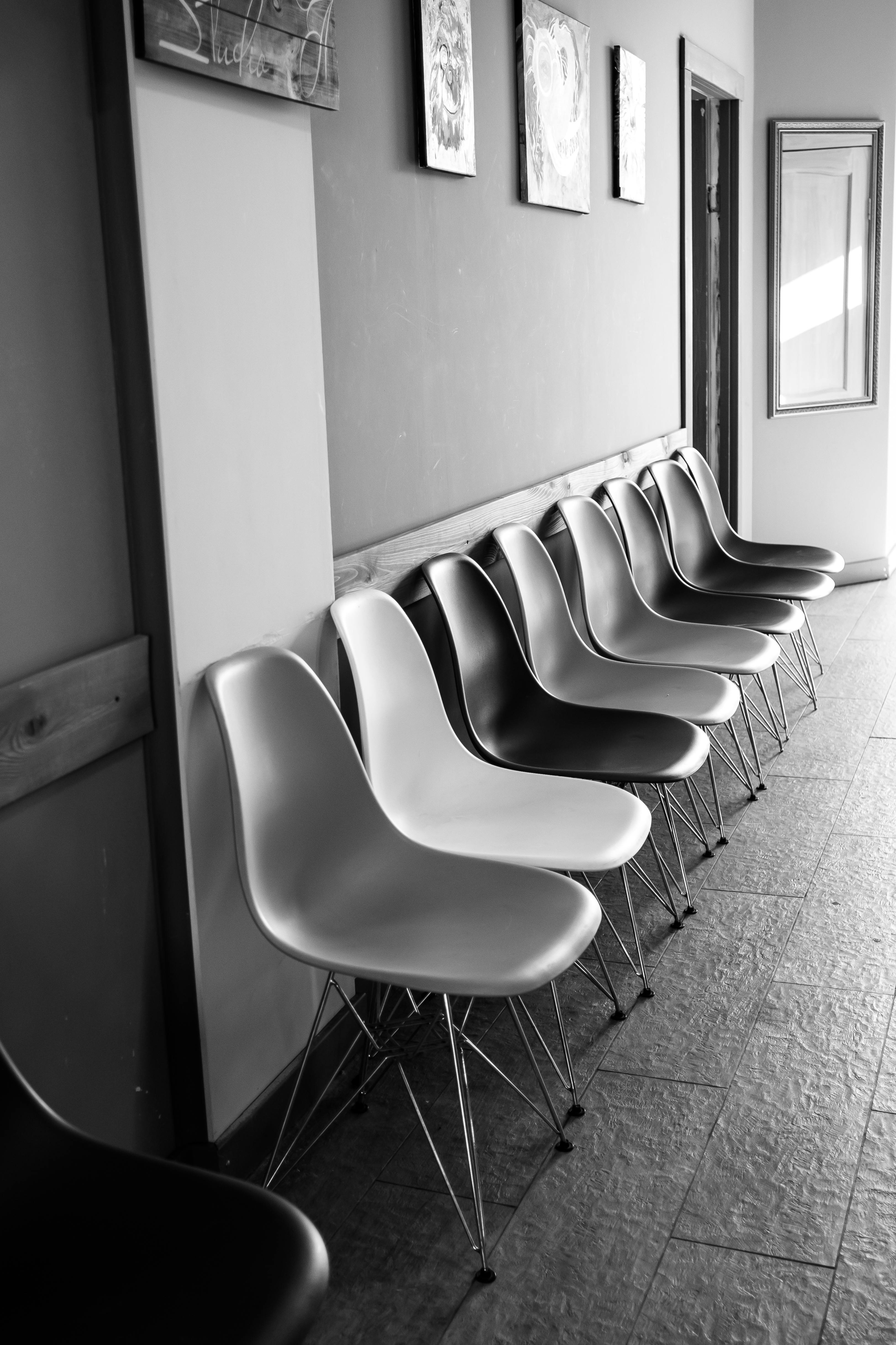 Monochrome photo of empty chairs in a waiting area with wall art.