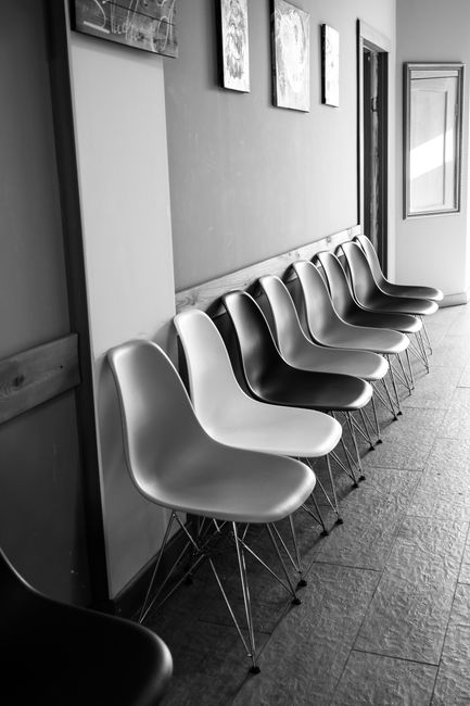 Monochrome photo of empty chairs in a waiting area with wall art.