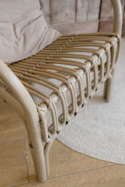 Close-up of a stylish woven armchair and pillow, offering comfort and elegance in a minimalist décor.
