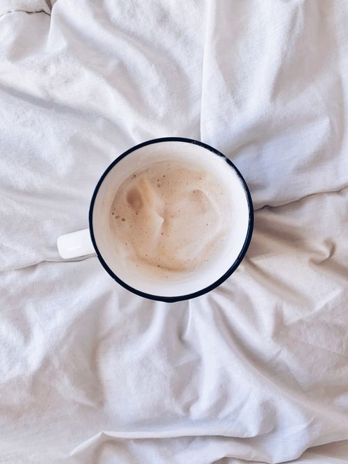 Free A creamy cappuccino atop soft white bedding, creating a warm and inviting atmosphere. Stock Photo