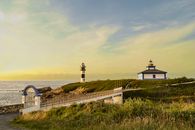 Beautiful seaside scene with Faro Illa Pancha lighthouse and footbridge at sunset on the Galician coast.