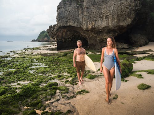Free Man and Woman Carrying Surfboards Walking on Beachside Stock Photo