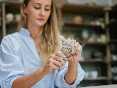 Focused woman crafting clay with detailed handwork in a pottery studio setting.