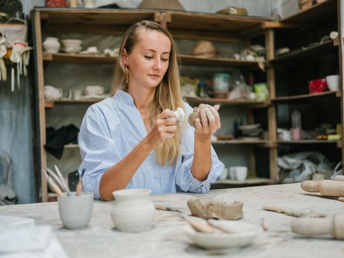 Free A woman artisan skillfully molds clay into pottery in her workspace. Stock Photo