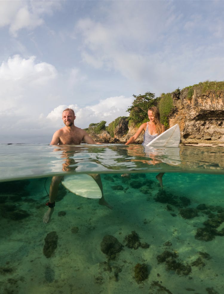 Couple With Boards Swimming In Water