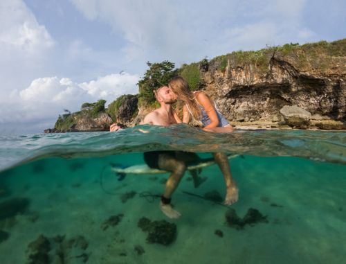 Free A charming couple shares a kiss on a tropical beach, enjoying sun and sea. Stock Photo