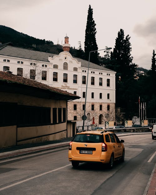 Yellow Car on a Road and White Building Facade in Background