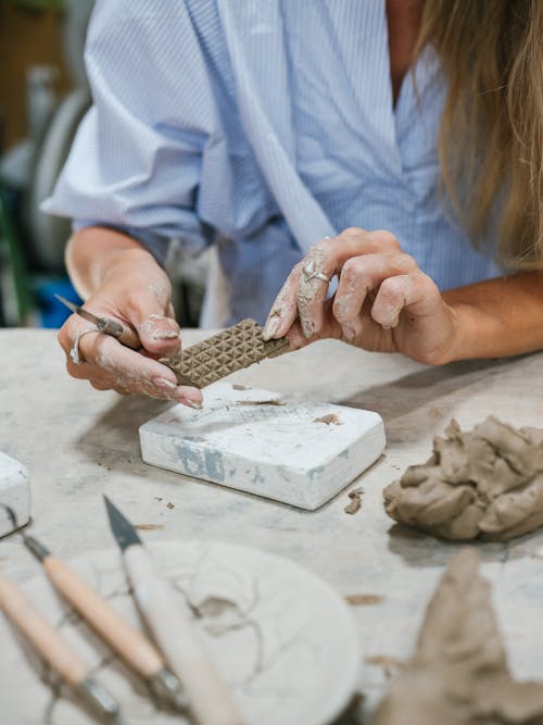 Woman in Blue Shirt Holding Piece of Clay