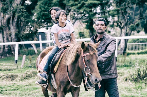 бесплатная Дети верхом на лошади в сопровождении взрослых Стоковое фото