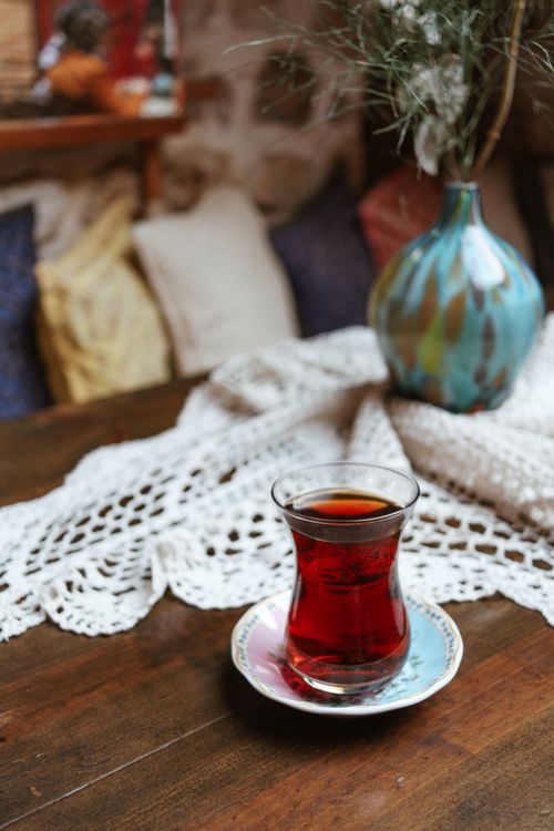 Free Turkish glass of freshly brewed tea on wooden table with dry plant sprigs in decorative vase in house Stock Photo