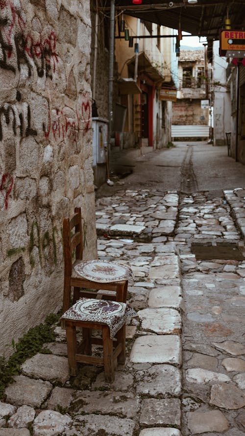 Chair and stool on cobblestone pavement in old town