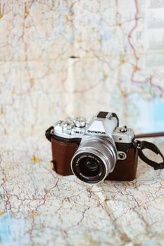 Professional vintage photo camera with lens and strap on paper guide with curved routes on blurred background