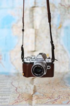 Vintage camera hanging against a world map backdrop, capturing travel vibes.