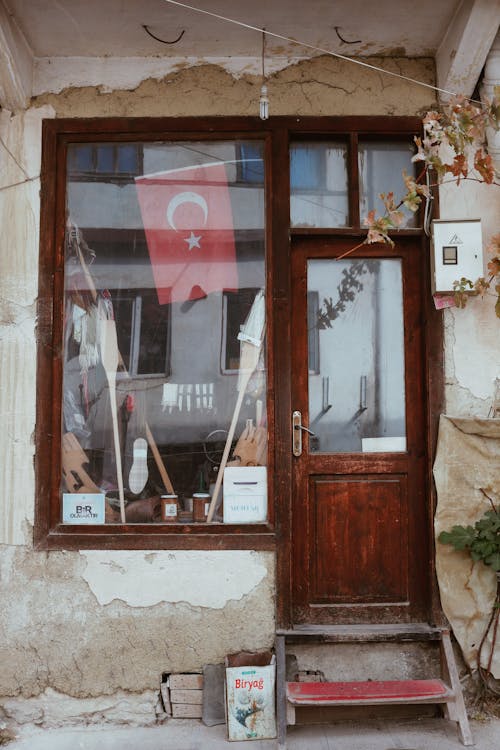 Aged building exterior with entrance door and national flag of Turkey behind window in city