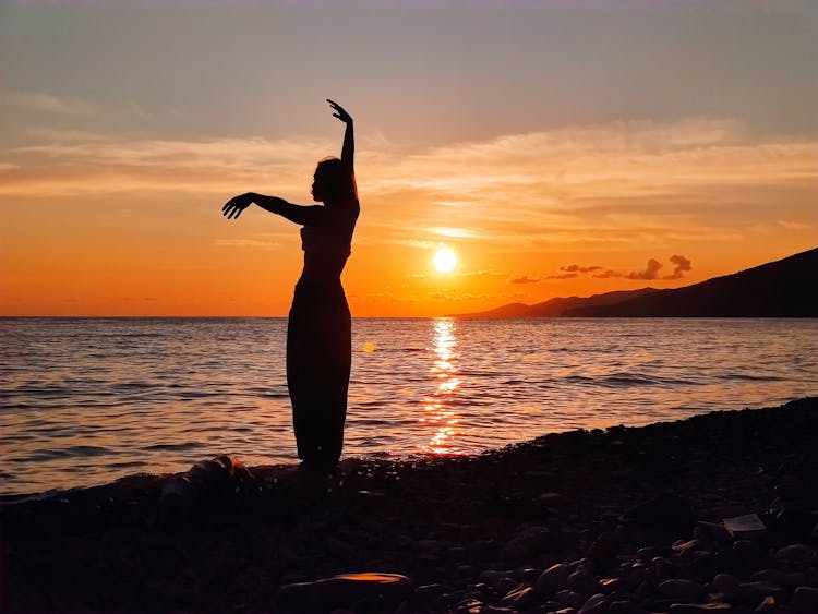 Silhouette Of Woman Standing On Shore