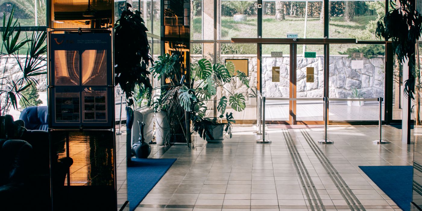 Modern hotel lobby with a glass entrance, seating and indoor plants