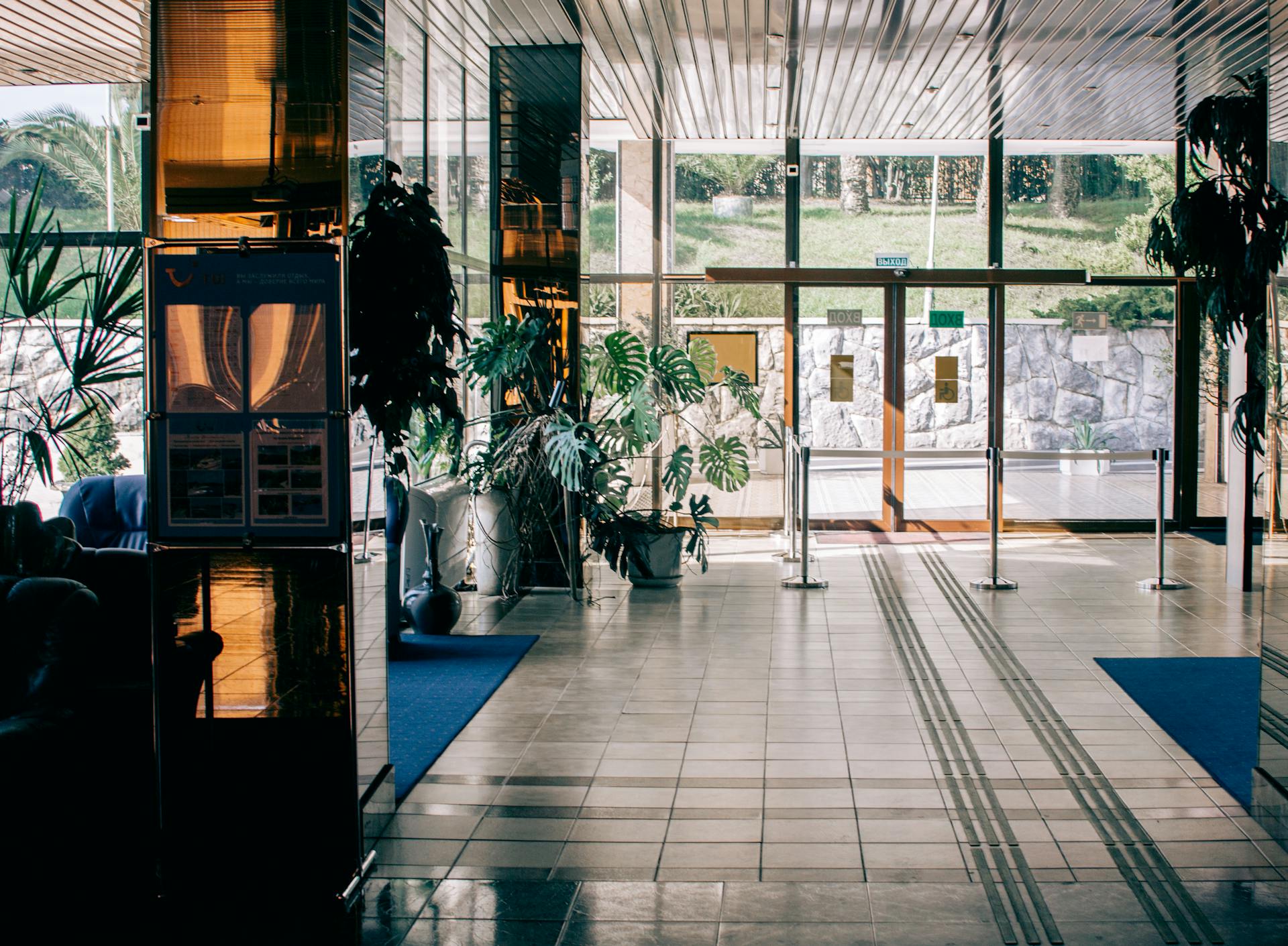 Elegant modern hotel lobby with glass entrance, luxurious design, and indoor plants.