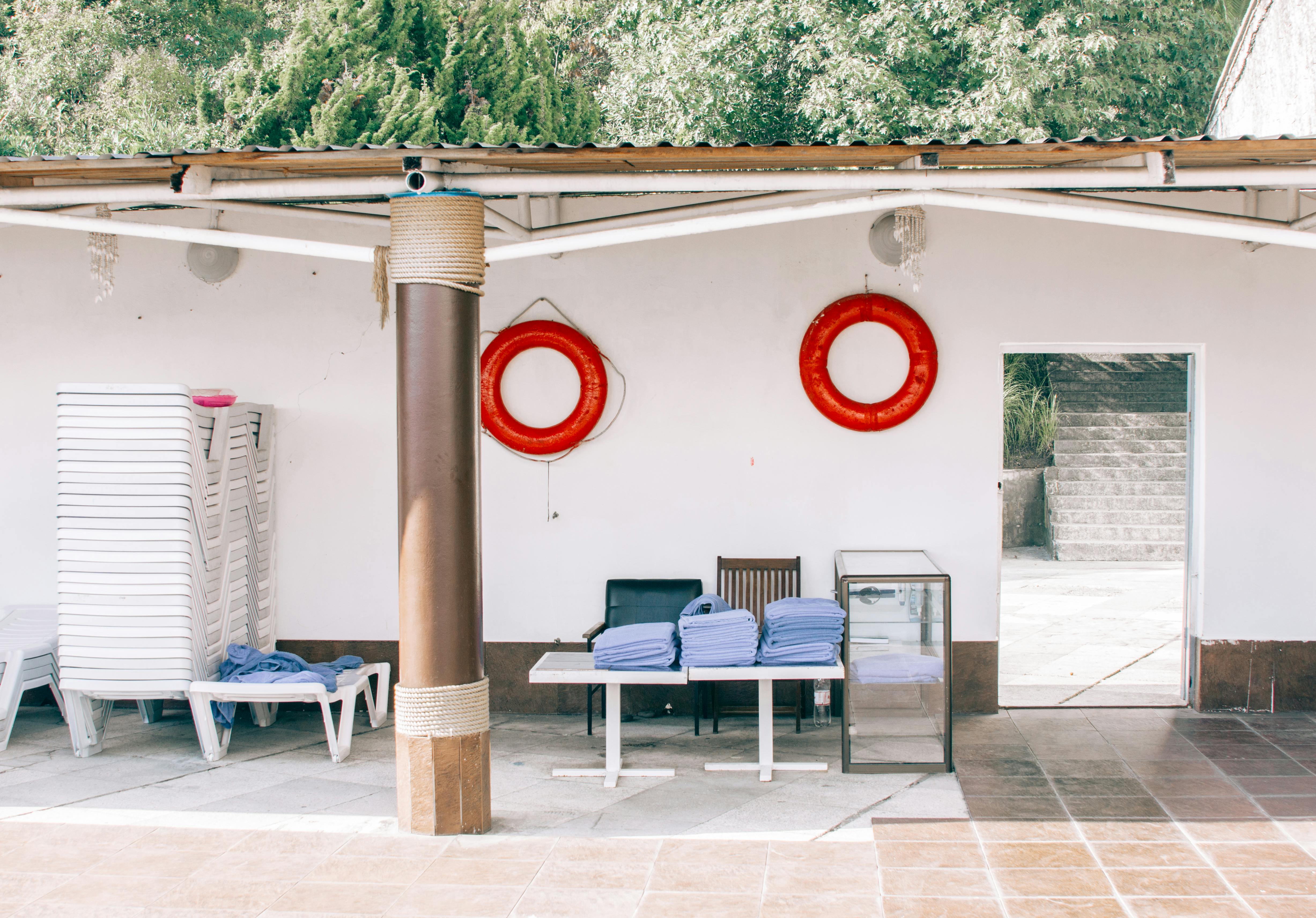 Pile of Blue Garment on Top of Two White Pedestal Tables Near Two Chairs \u00b7 Free Stock Photo