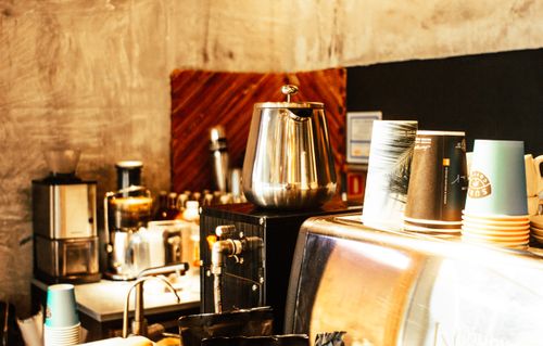 Free Warm café setting featuring coffee machines, cups, and a rustic interior. Stock Photo