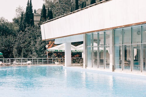 Ücretsiz Mavi Yüzme Havuzu Yanında Beyaz Ve Gri Beton Bina Stok Fotoğraflar