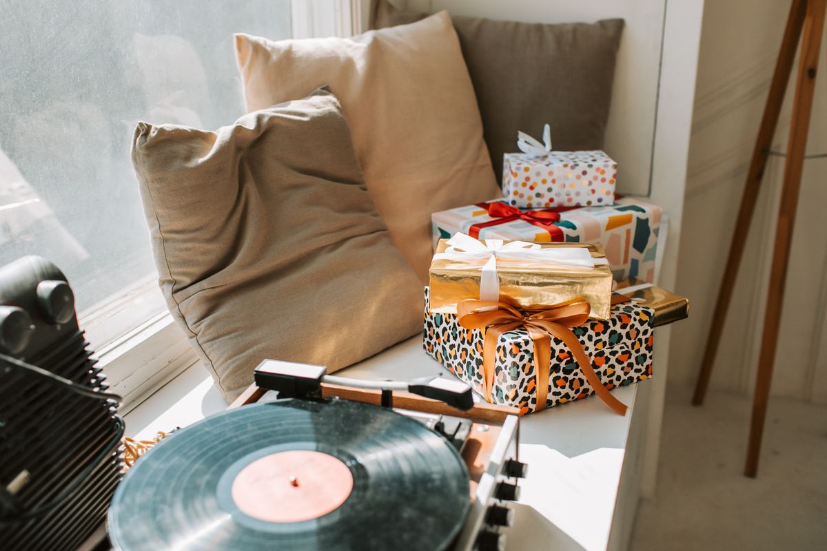 Gift boxes stacked beside a vinyl record player on a windowsill in warm afternoon light