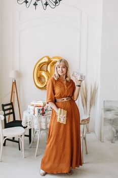 Charming senior woman celebrating her 60th birthday with gifts and decorations in a well-lit indoor setting.