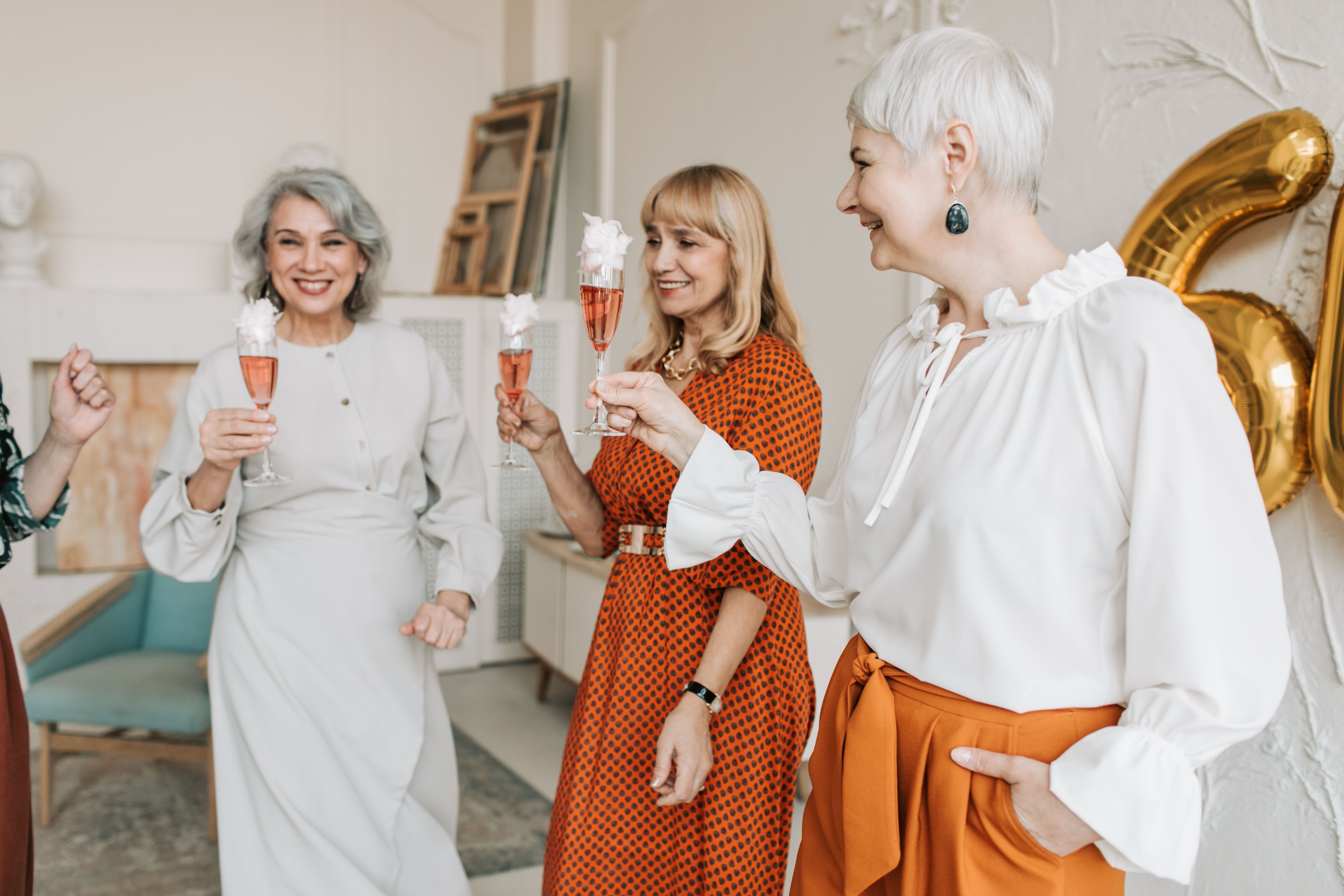 Three women celebrating with champagne during a joyful indoor gathering.