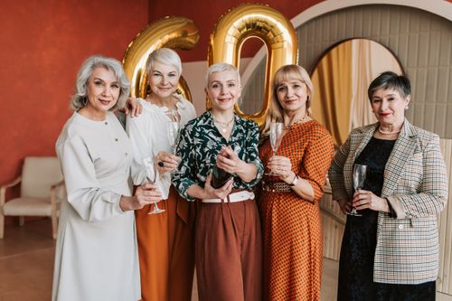 Free Five senior women joyfully celebrating a 60th birthday with champagne indoors. Stock Photo