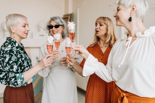 Free Cheerful senior women toasting with champagne glasses during a celebration indoors. Stock Photo