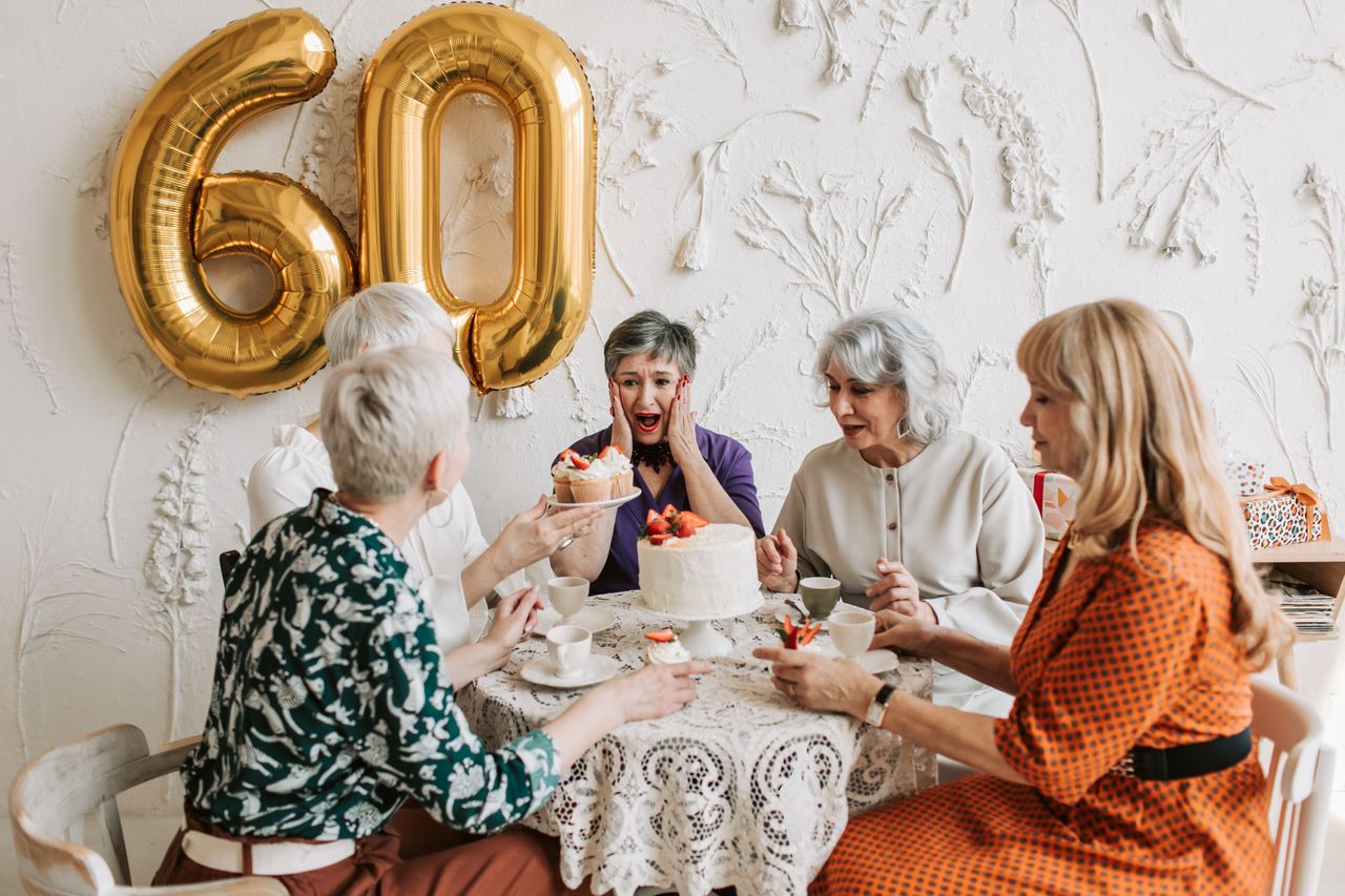 senior women joyfully celebrating a 60th birthday with cake and decora