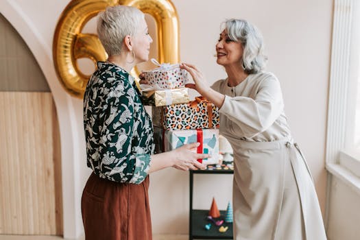 Two joyful senior women exchanging gifts during a 60th birthday celebration indoors.
