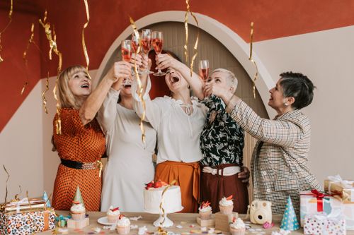 Free A group of senior women joyfully toasting with champagne at a festive celebration indoors. Stock Photo