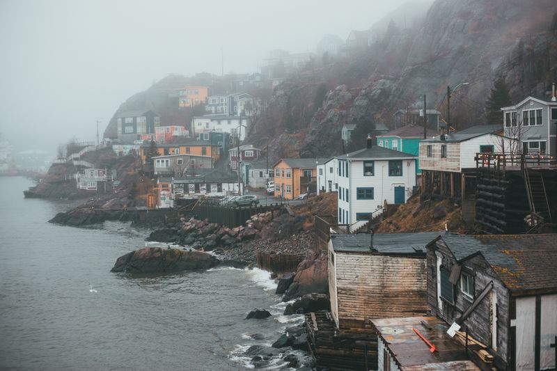 A fog-covered seaside village on a rocky shore — photo by Erik Mclean on Pexels