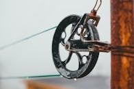 Wet pulley wheel with metal details attached to rusty pole with stretched rope on street against blurred background in rainy weather