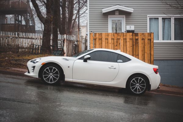 White coupe parked on a residential street, photo by Erik Mclean on Pexels