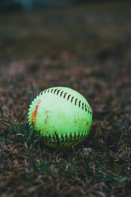 Close-Up Shot of a Green Baseball on a Grassy Field