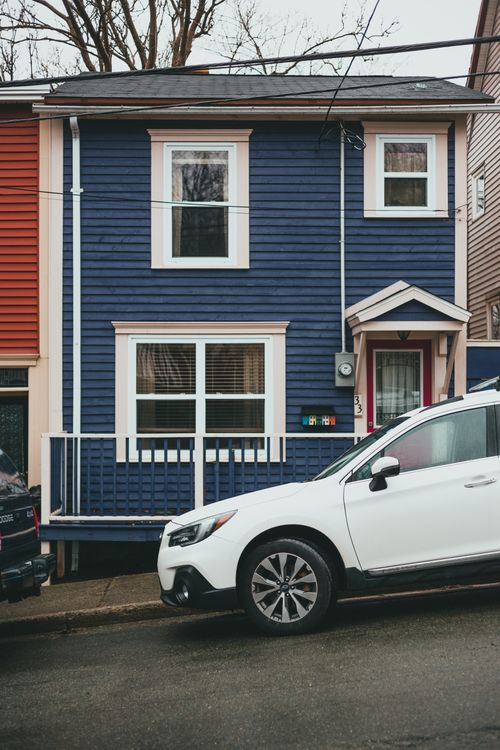 Free White car parked on asphalt road near residential blue house with white windows Stock Photo