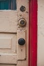 Fragment of shabby door of yellow color with round handle and cant painted red