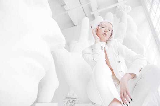 Stunning minimalist fashion portrait of a model in white attire, set in a bright indoor location.
