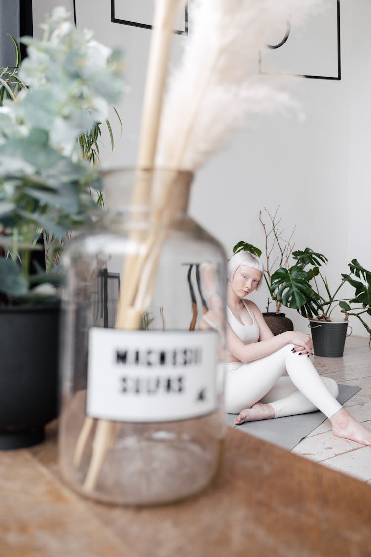 A Jar With Incense Sticks And Woman Sitting On A Yoga Mat In The Background 