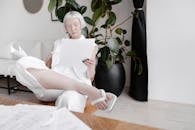 Woman in White Dress Sitting on Black Leather Couch