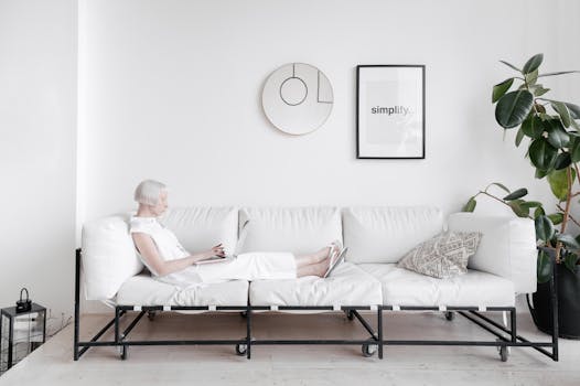 Elderly woman relaxing on a modern white sofa with a minimalist design theme.