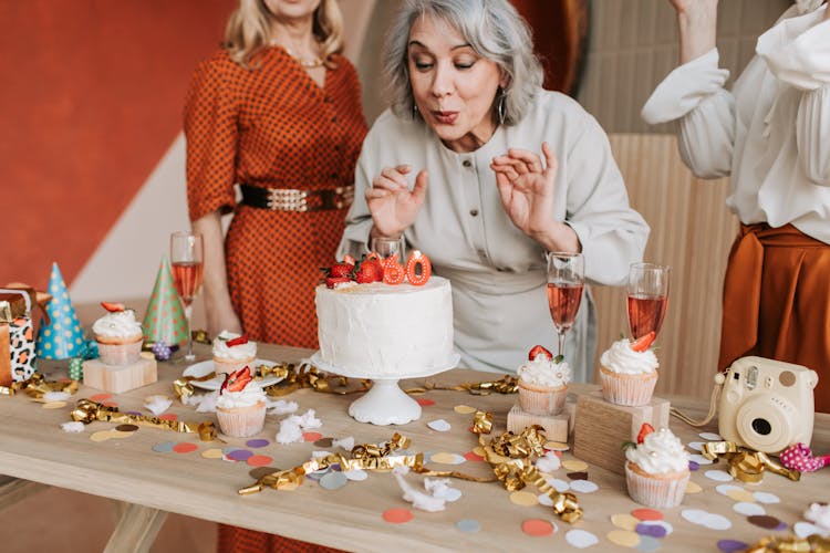 Woman In A Gray Dress Blowing The Candles On A Cake